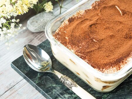 Traditional coffee tiramisu dessert with mascarpone cheese and cocoa powder in glass container on...