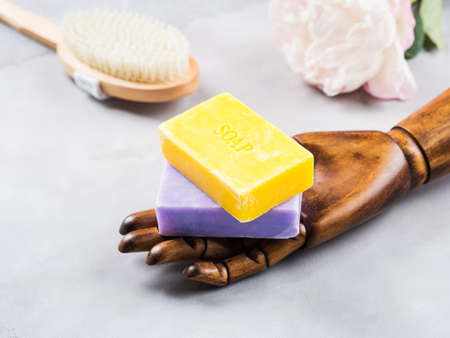 Lemon and lavender artisanal soap in dark wooden hand on marble table. Body care concept