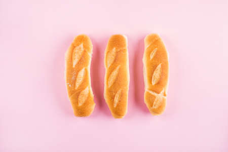 Three freshly baked mini baguette on pink background. Flat layの写真素材
