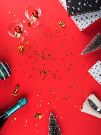 Red flat lay christmas or new year frame background with gift boxes, champagne bottle and festive golden decorの写真素材