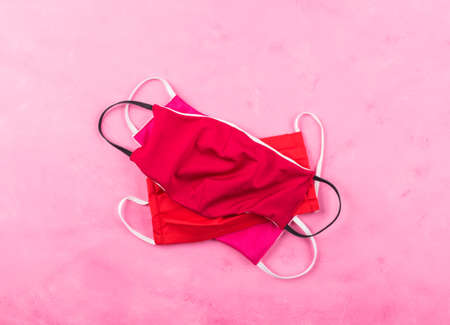 Hand made red face masks protection on pink background. New normal fashion in times of Coronavirus...