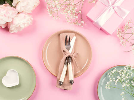 Pink flat lay with peonies decor flowers and pastel tableware. Festive occasion spring summer table...