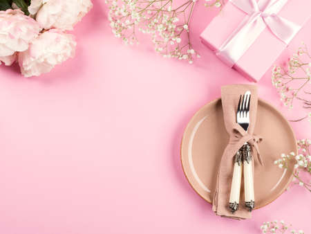 Pink flat lay with peonies decor flowers and pastel tableware. Festive occasion spring summer table...