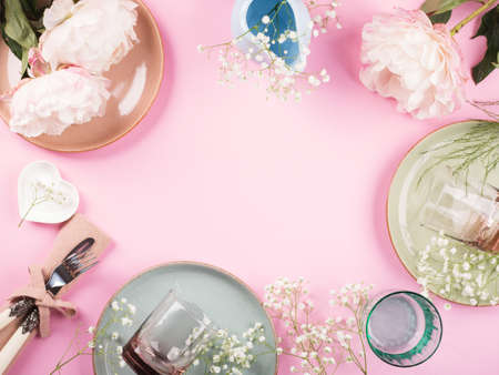 Pastel color crockery tableware frame with peonies on pink backgroundの写真素材