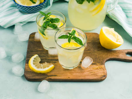 Fresh lemonade in jug and glasses with ice, mint leaves and lemon slices on bright gray and blue background. Top viewの写真素材