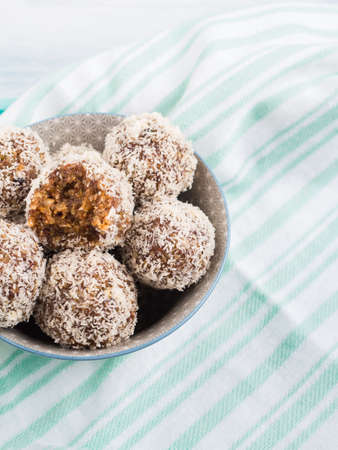 Home made vegan energy protein balls with coconut flakes, almond butter, oats, nuts, dates, dried fruit, flax and hemp seeds served in bowl on turquoise napkinの写真素材
