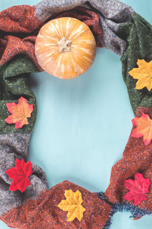 Cozy red and green scarf with autumn leaves on turquoise background. Frame flat layの写真素材