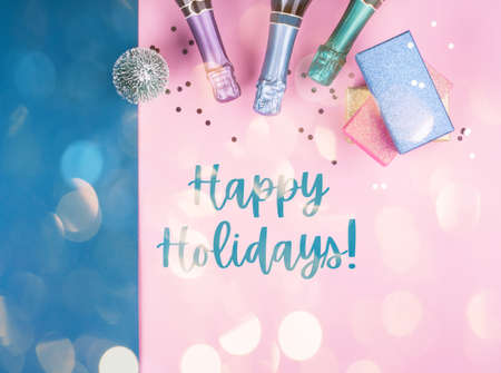 Champagne bottle, gifts and confetti on pink and blue background with sparkling confetti. Text...