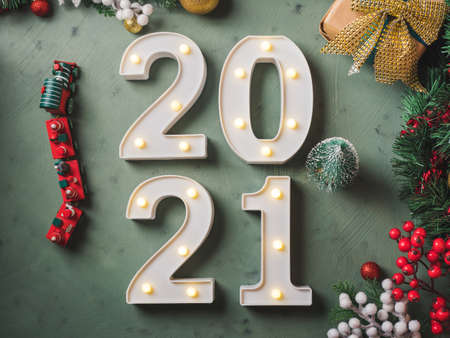New year festive green background with 2021 illuminated numbers with ornament and toy train and tree...