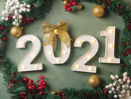 New year festive green background with 2021 illuminated numbers with ornament and baubles on dark green.の写真素材