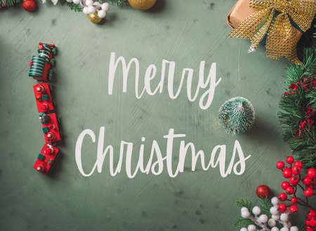 Christmas festive dark earthy green background with toy wooden vintage train and small tree. Moody frame flat lay with greetings textの写真素材