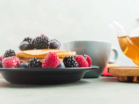 Stack of pancakes with fresh berries served in a dish with green tea. Hero viewの写真素材