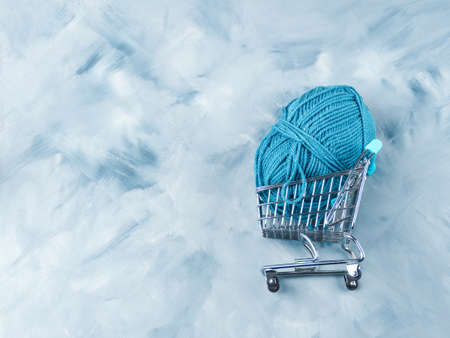Blue wool knitting yarn in shopping cart on faded background. Copy spaceの写真素材