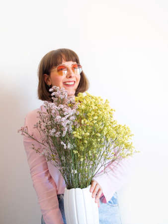 Young woman in pink shirt with vase of dried colorful flowers
