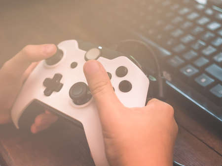Little kid playing with joystick gamepad in front of PC at emulated video game. Closeup