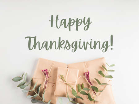Zero waste holiday gifts wrapped in paper with dried flowers on gray background. Happy thanksgiving greeting card textの写真素材