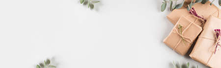 Zero waste holiday gifts wrapped in paper with dried floral decor on gray background. Web bannerの写真素材