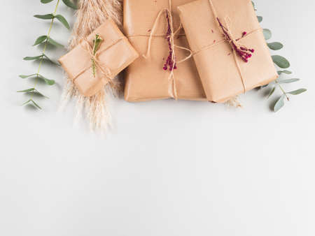 Zero waste holiday gifts wrapped in plastic free paper with dried floral decor on gray background.