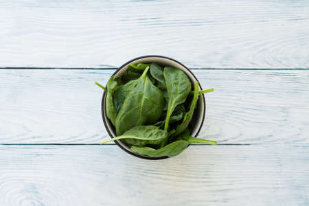 Rustic closeup of green spinach leaves on white wooden table background. Flat lay top view.の写真素材