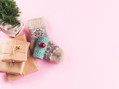 Minimal Christmas flat lay on pink with cozy socks, stack of gift boxes, green twine and wrapped plant tree. Top viewの写真素材