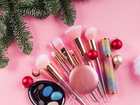 Christmas spruce branches, santa cap and presents with shiny make up tools, products on pink background. Festive beauty gift conceptの写真素材