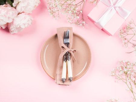 Pink flat lay with peonies flowers and pastel tableware. Festive occasion spring summer table setting conceptの写真素材