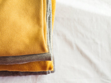 Yellow illuminated color and gray winter sweaters stack. Trendy fashion autumn warm and cozy...