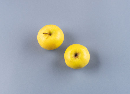 Illuminated yellow apples on dark gray background. Trendy colors flat lay