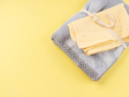 Folded yellow and gray kitchen cloth textile napkins on yellow background. Trendy home design colorsの写真素材