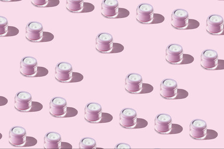 White antiaging face cream in pastel purple jar on pink background. Beauty skin care product patternの写真素材
