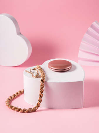 Fashion valentines day backgound with golden accessories display on white heart podium over pinkの写真素材