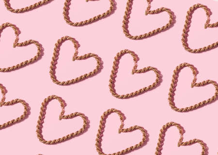 Trendy valentines day backgound with golden necklace heart and hard shadow on pink.の写真素材
