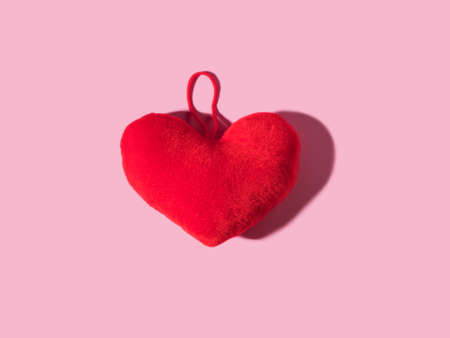 Trendy Valentines day backgound with stuffed red heart and hard shadow on pink. Love symbol conceptの写真素材
