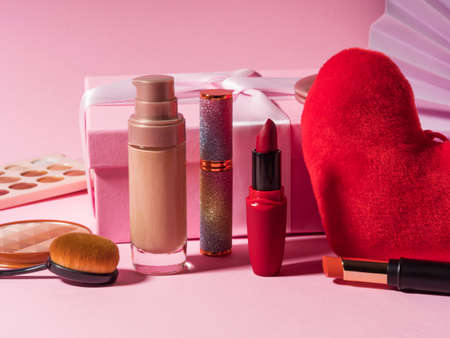 Cosmetics beauty make up products background with red heart and gift box on pink. Valentines dayの写真素材