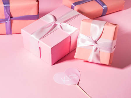 Pink wrapped gift boxes with ribbons on monochrome background with pink heart