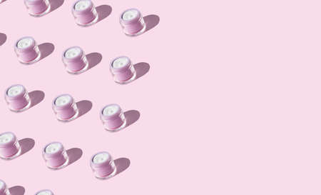 White antiaging face cream in pastel purple jar on pink background. Beauty skin care product patternの写真素材