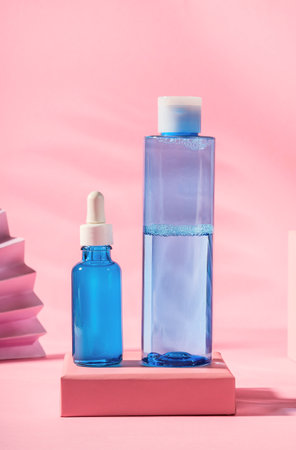 Hyaluronic acid oil serum generic bottle treatment and toner on pink geometric background with pastel color paper fanの写真素材