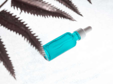 Hyaluronic acid serum generic bottle treatment on white background with unfocused golden plant