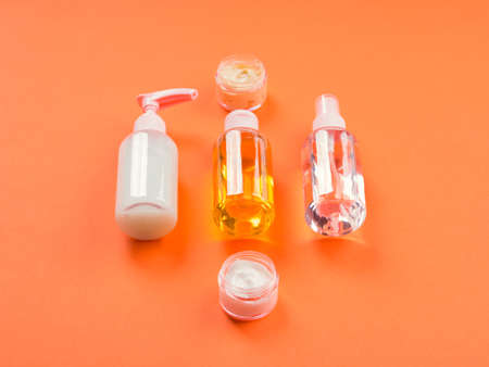 Generic beauty products on orange background. Lotion, tonic, cleanser in bottlesの写真素材
