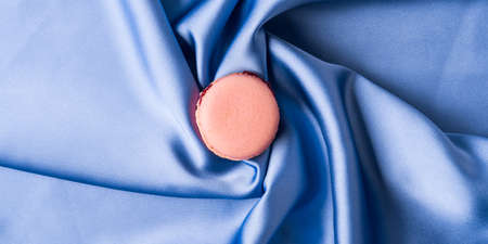 Pastel pink french macaroons on blue silk fabric backgroundの写真素材