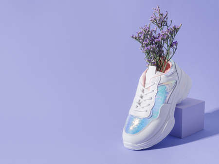 White female sneakers with sequins with flowers inside on purple background with geometric cube podiumの写真素材