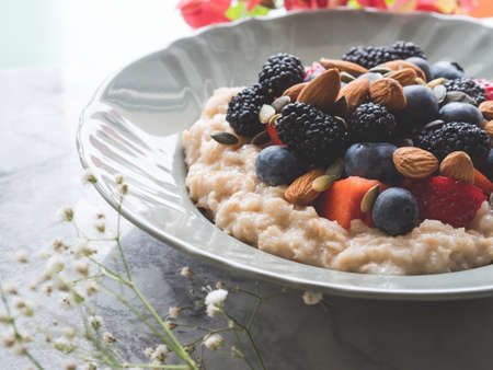 Delicious breakfast oat porridge on plant milk with nuts and berries on marble tableの写真素材