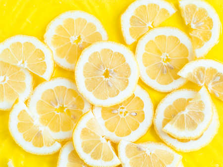 Lemon citrus slices in water with ripples, bold yellow texture summer backgroundの写真素材