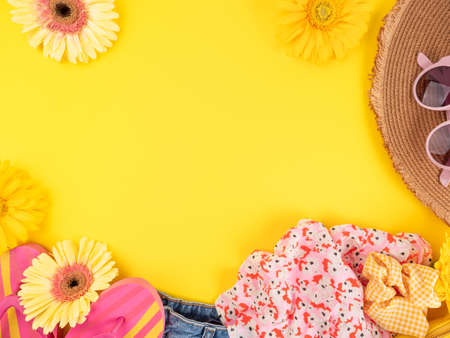 Summer fashion outfit background with straw hat, jeans, flip flops, sunglasses, handbag on yellowの写真素材