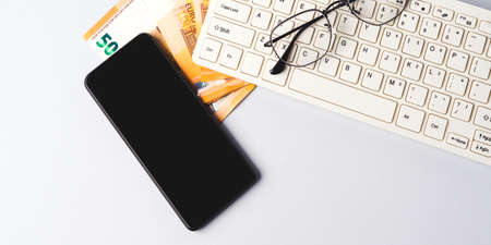 Euro money banknotes, keyboard, smartphone and glasses, online banking, business, student loan conceptの写真素材