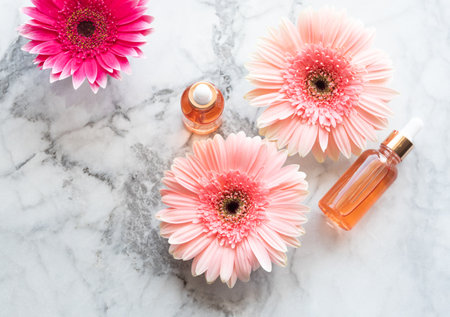 Pink flowers and beauty serum in dropper bottles on marble table. Skin care concept