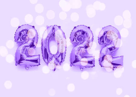2022 new year numbers in foil balloons decor on purple background with festive lightsの写真素材