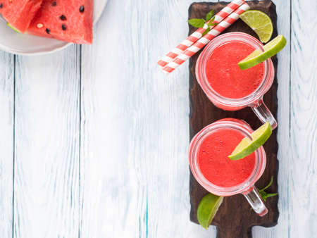Watermelon smoothie with lime and mint in mason jar on white wooden background. Overhead shotの写真素材
