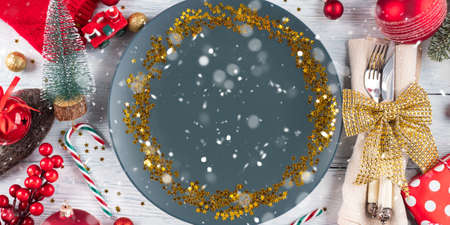 Christmas festive dinner table setting with blue empty plate with golden star confetti and decorの写真素材