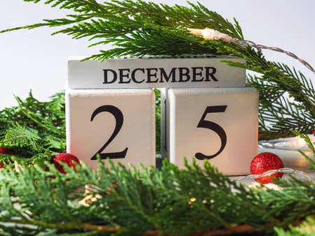 December 25 Cristmas celebration date on calendar in frame of green branch and red holiday decor